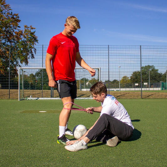 Neuroathletik Neuro Fußball Kevin Grafen macht eine sensorische Integration von Fuß und Knie mit einem Fußballer.